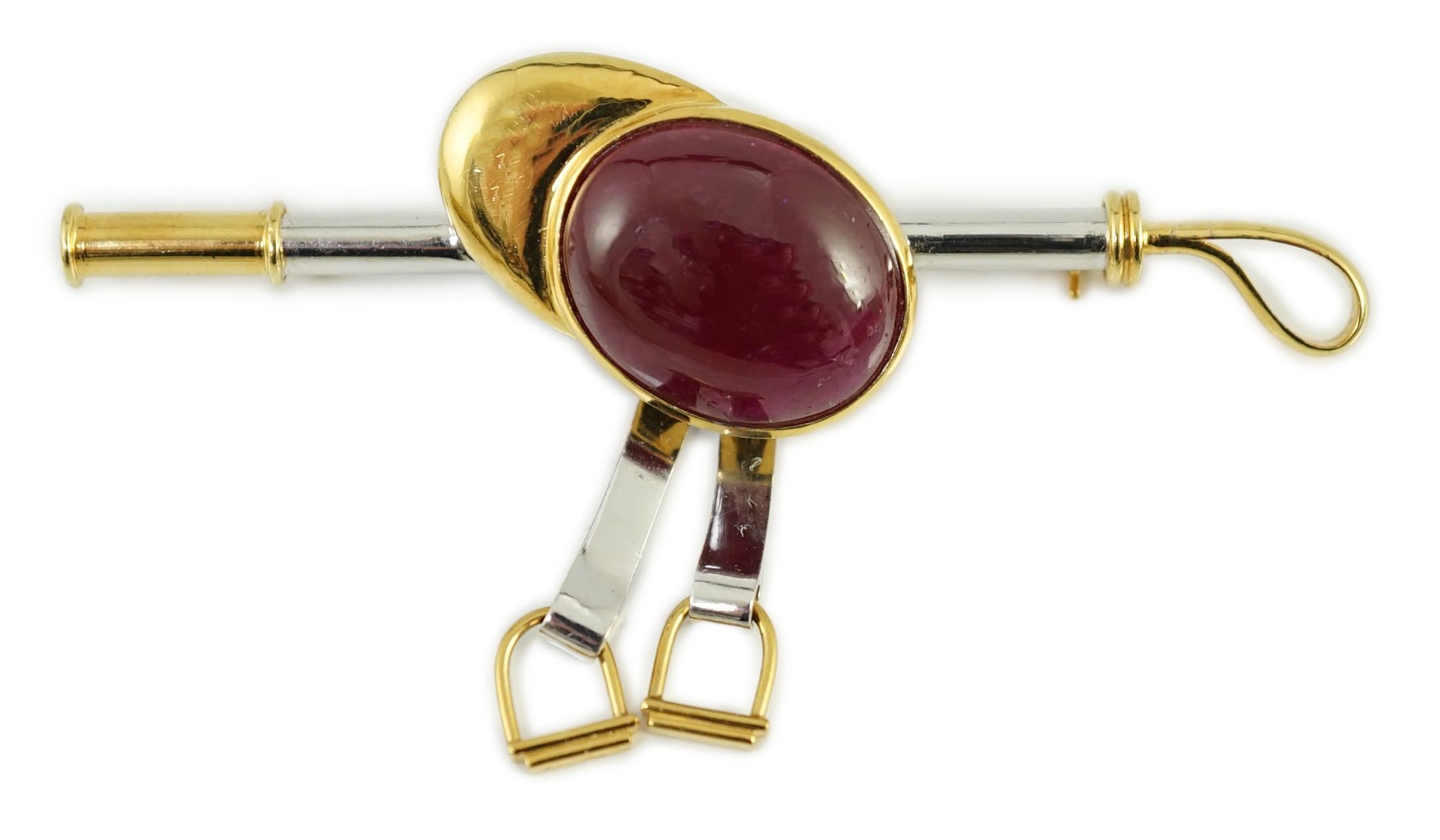 A late 20th century 18ct yellow and white gold, cabochon ruby set ‘jockey cap, riding crop and stirrups’ drop bar brooch